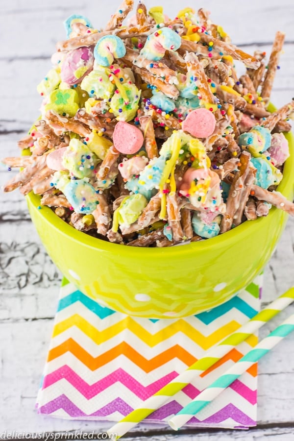 Rainbow napkins are placed underneath a full bowl of snack mix.