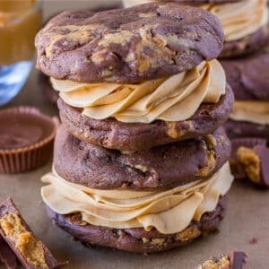 An up-close shot of two stacked chocolate peanut butter whoopie pies on the counter with crumbled peanut butter cups.