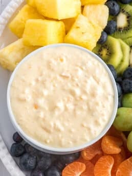 Creamy Pineapple Fruit Dip pinterest pin with an overhead shot of the pin on a plate with fruit.