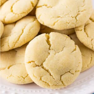 A closeup of a pile of sugar cookies on a white plate.