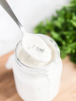 ranch dressing in mason jar while holding spoon over