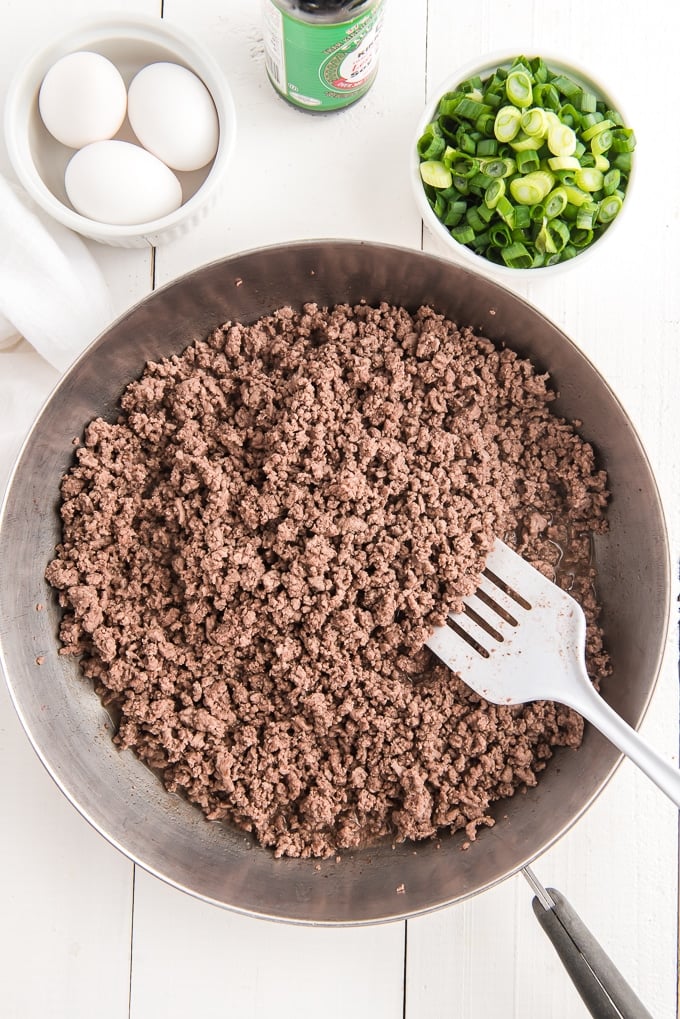 Ground beef is being cooked in a large skillet.