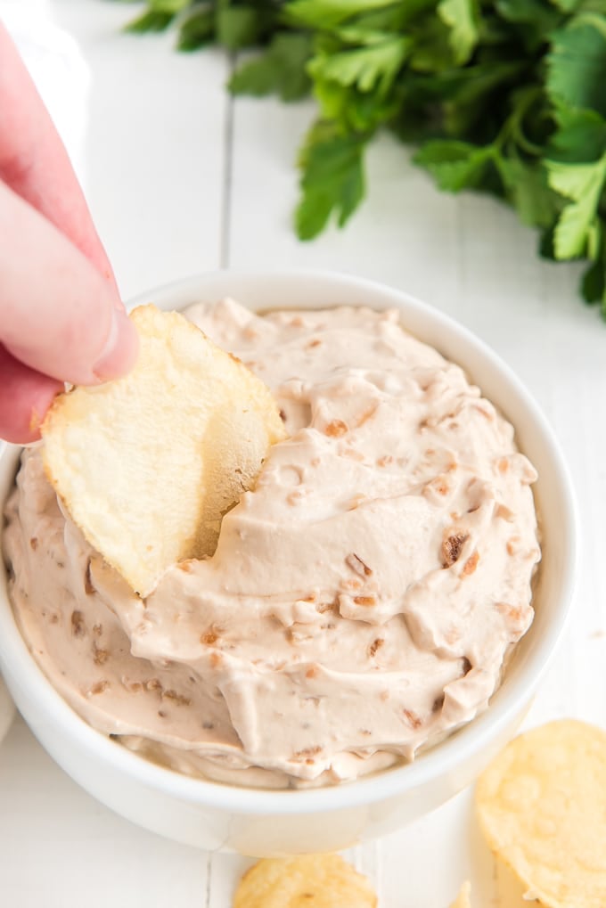 A chip is dipped into the French onion dip.