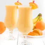 Two glasses of orange smoothie side by side.