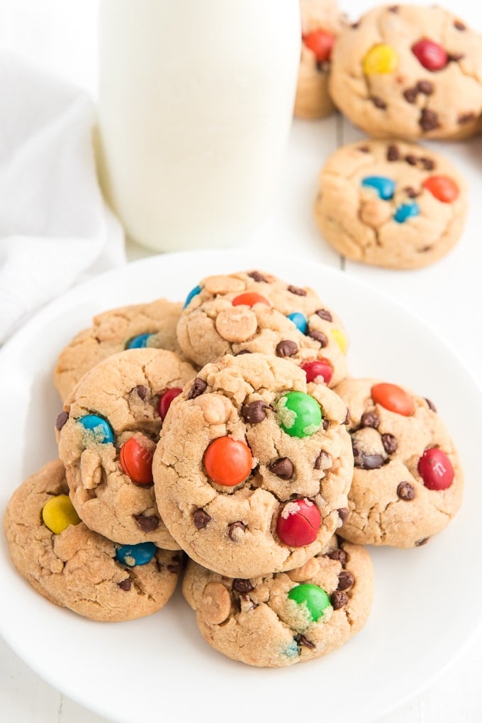 Cookies are presented in a stack on a white plate next to a glass of milk. 