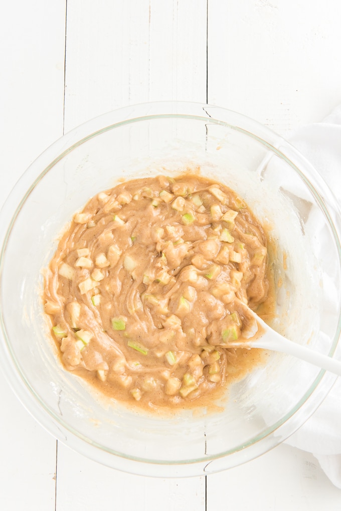 Apple bread batter is mixed in a glass bowl. 