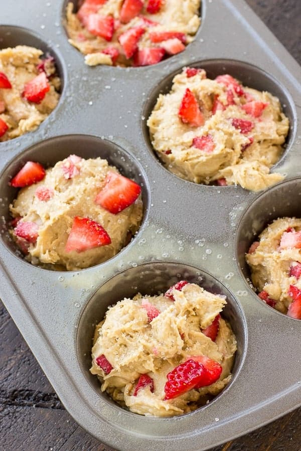 Uncooked strawberry muffins are placed in baking tins.