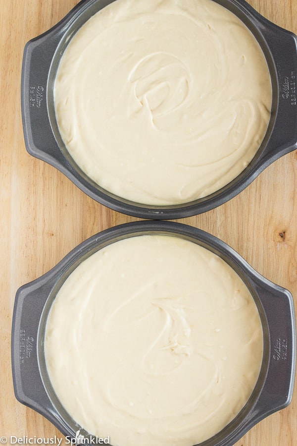Two cake pans are filled halfway with cake batter.