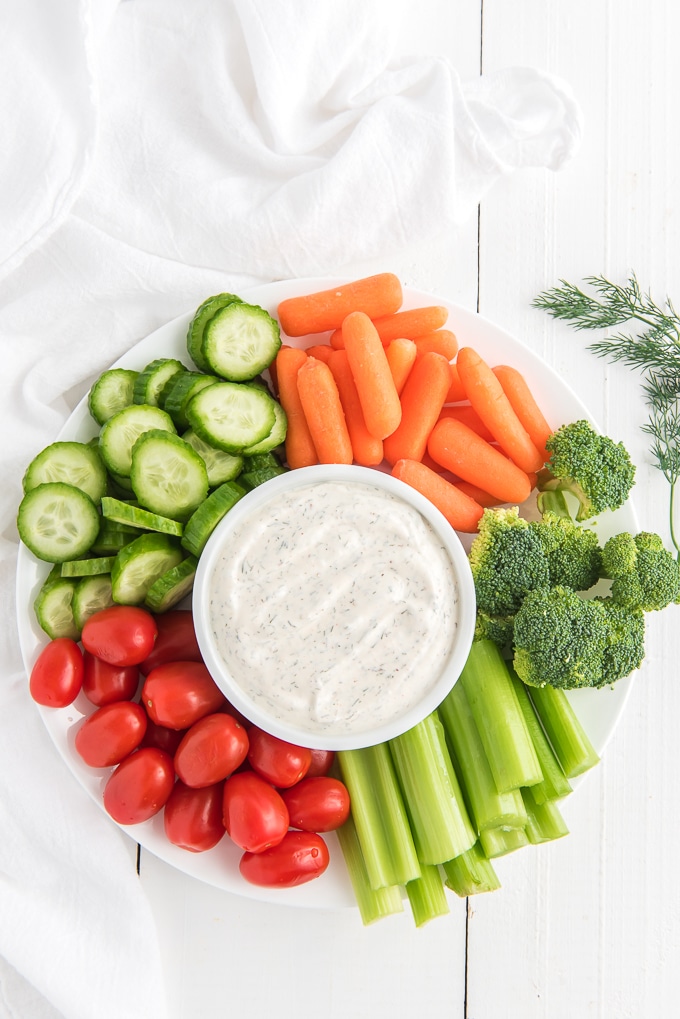Veggies are placed around a small white bowl of dip.