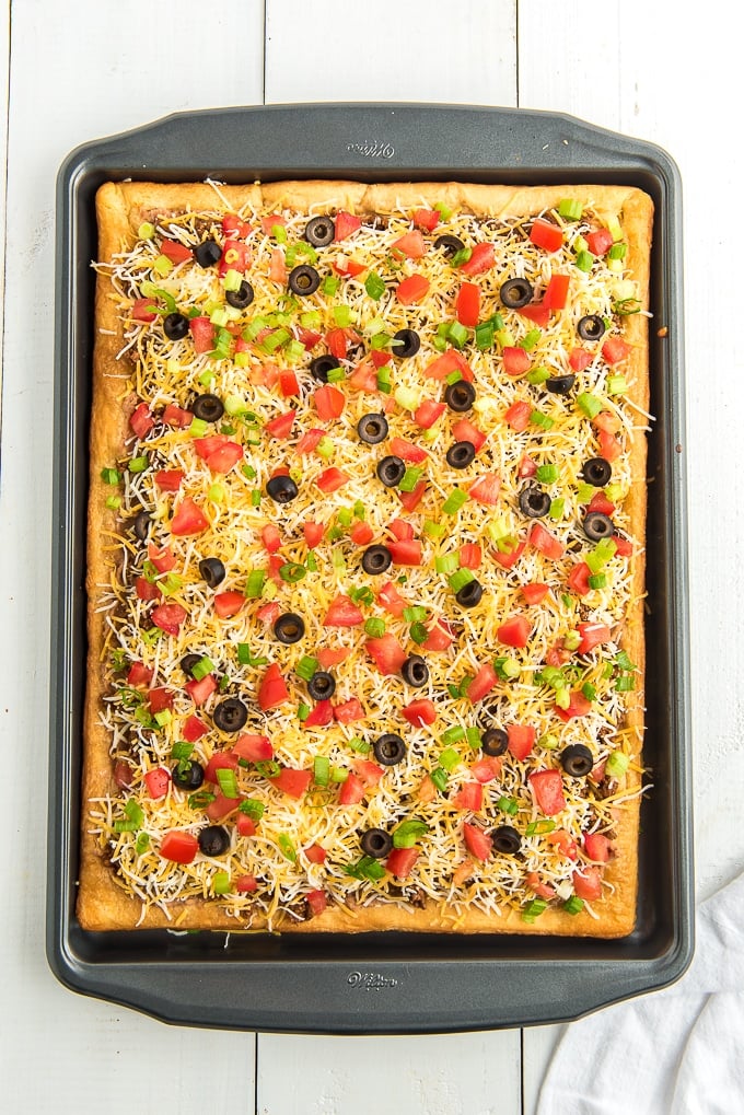 taco pizza topped with fresh tomatoes and olives