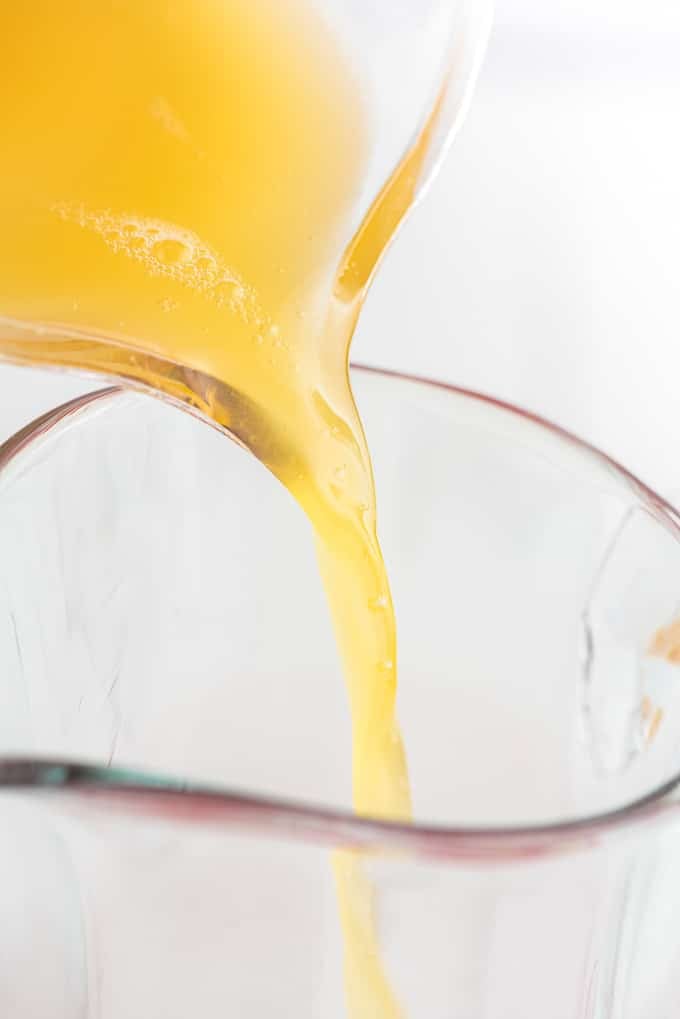 orange juice pouring into pitcher for holiday punch