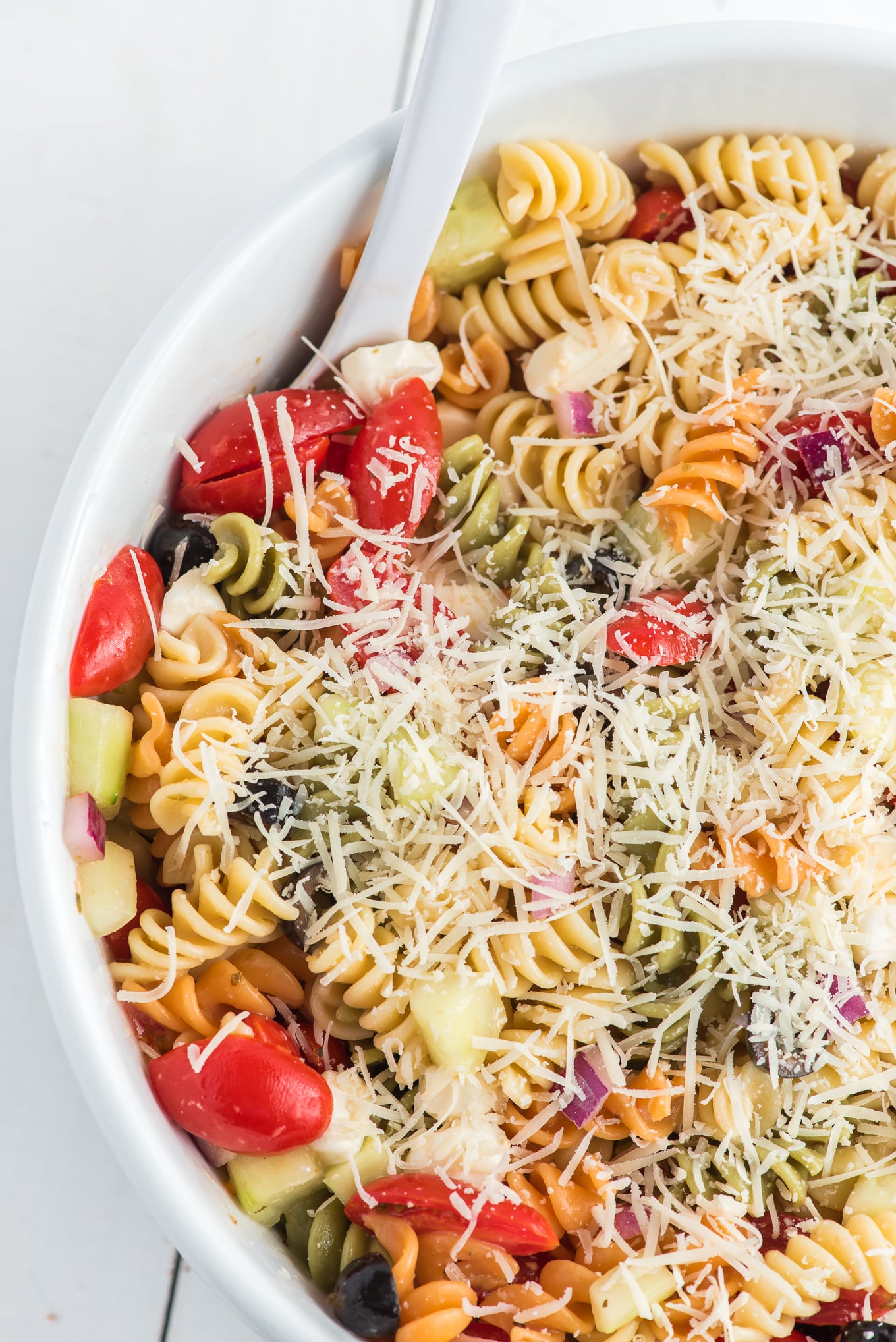 Pasta salad in serving bowl / Easy Pasta Salad is the best cold pasta salad with tri color pasta, tomatoes, cucumbers, onions, and mozzarella cheese tossed in olive garden Italian dressing. 