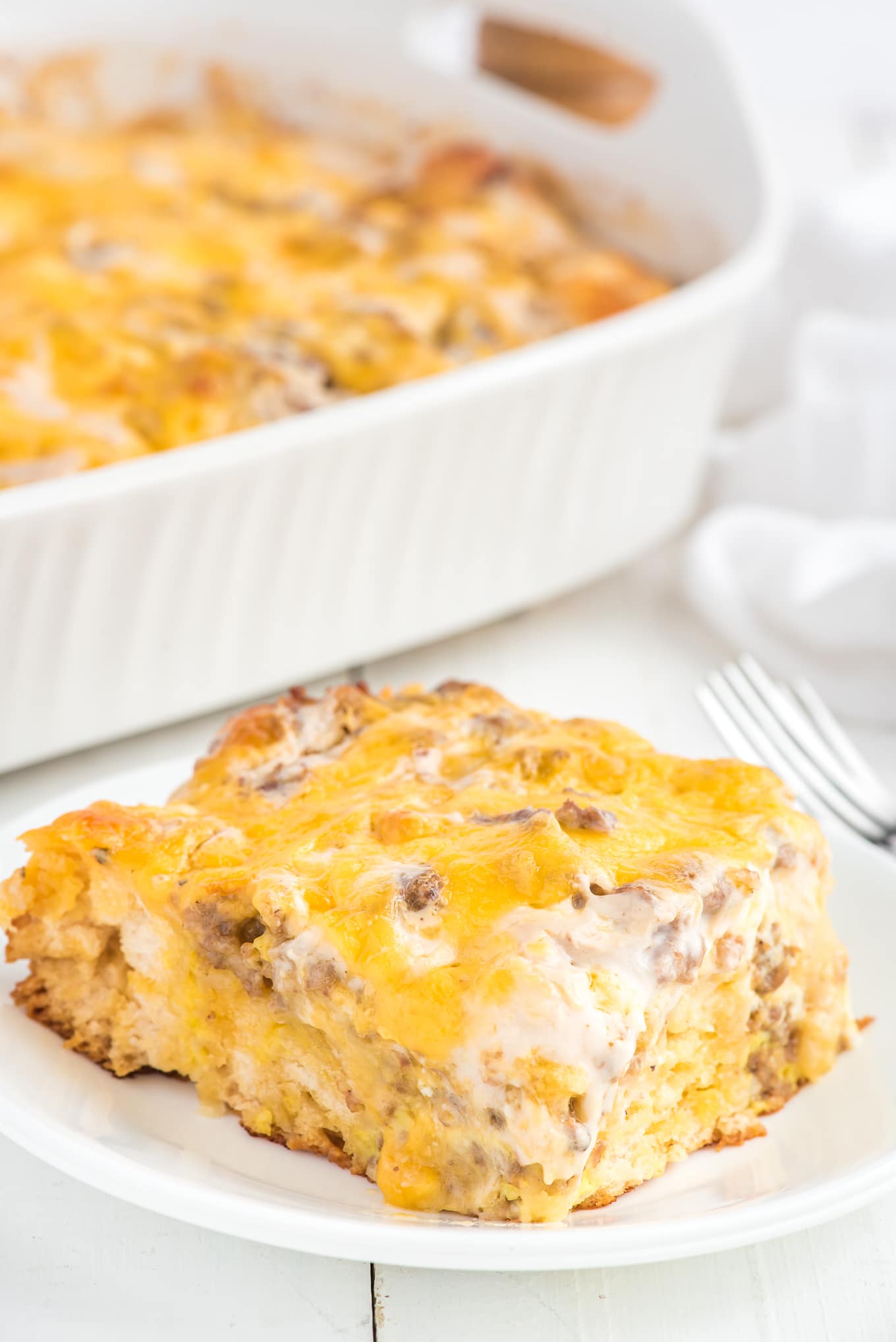 Breakfast casserole on a plate with a casserole dish in the background.