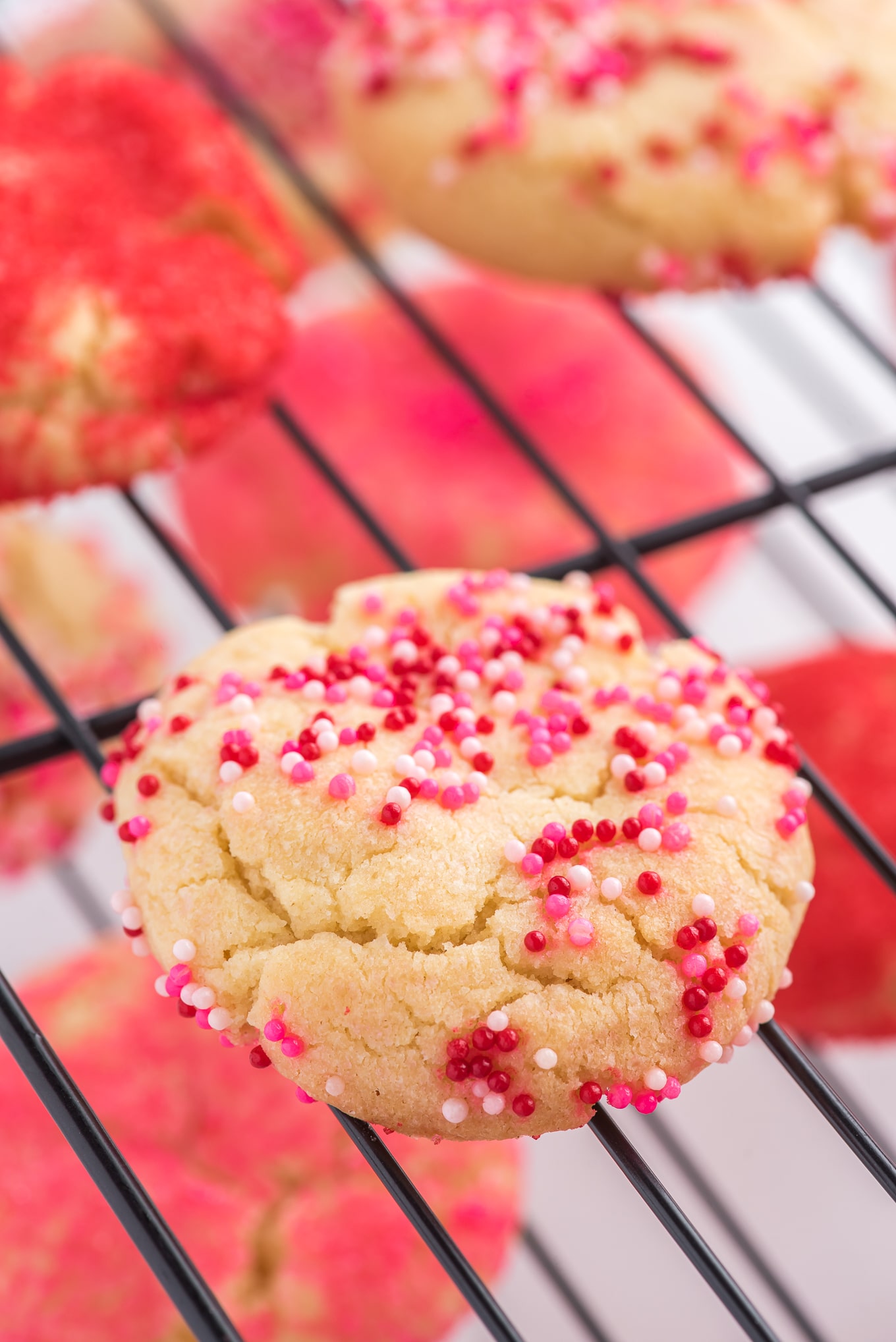 Valentine cookies on drying rack. / Valentine cookies are soft and chewy sugar cookies rolled in colored sugar and sprinkles. They are perfect for Valentine's Day dessert!