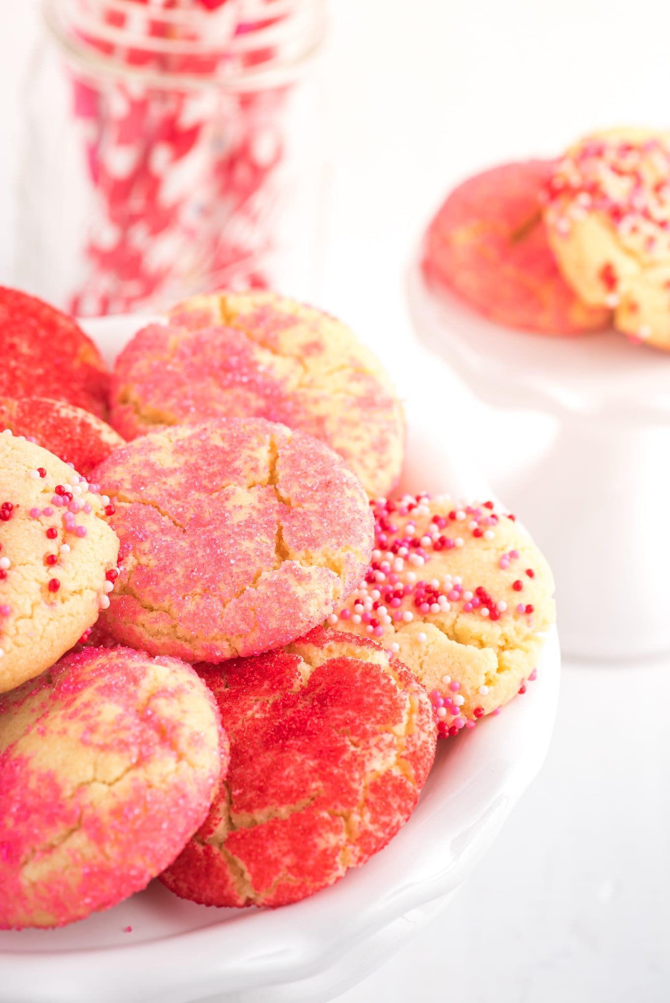 Valentine Cookies with sprinkles on white cookie tray. / Valentine cookies are soft and chewy sugar cookies rolled in colored sugar and sprinkles. They are perfect for Valentine's Day dessert!