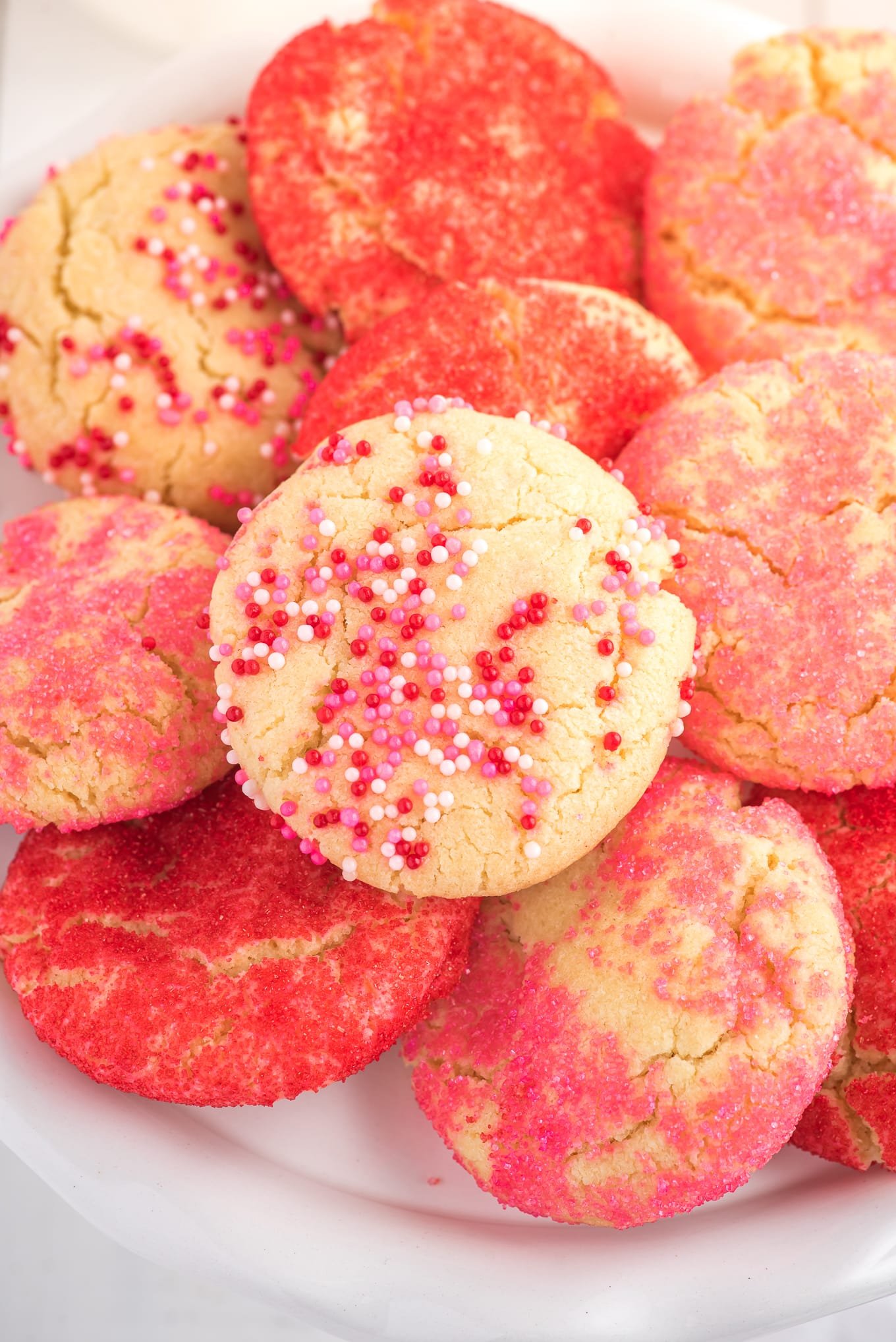 Valentine cookies on stacked on a plate. / Valentine cookies are soft and chewy sugar cookies rolled in colored sugar and sprinkles. They are perfect for Valentine's Day dessert!