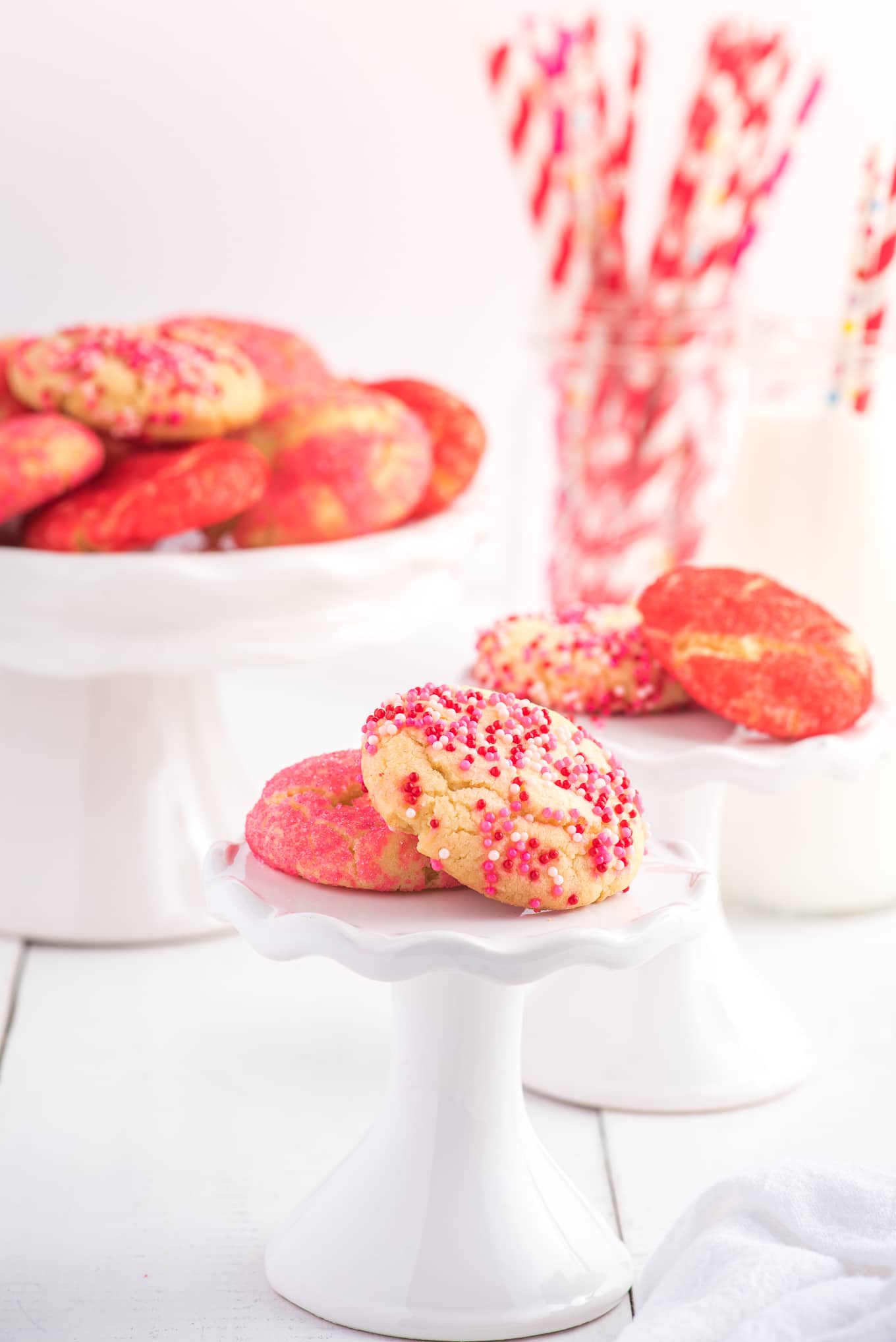 Valentine cookies on cake stand with milk. / Valentine cookies are soft and chewy sugar cookies rolled in colored sugar and sprinkles. They are perfect for Valentine's Day dessert!