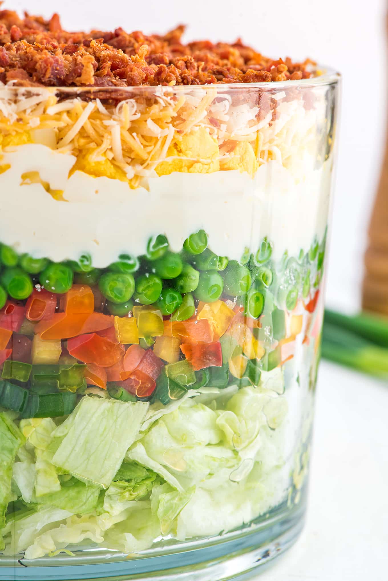 A colorful layered salad in a glass dish on the table.