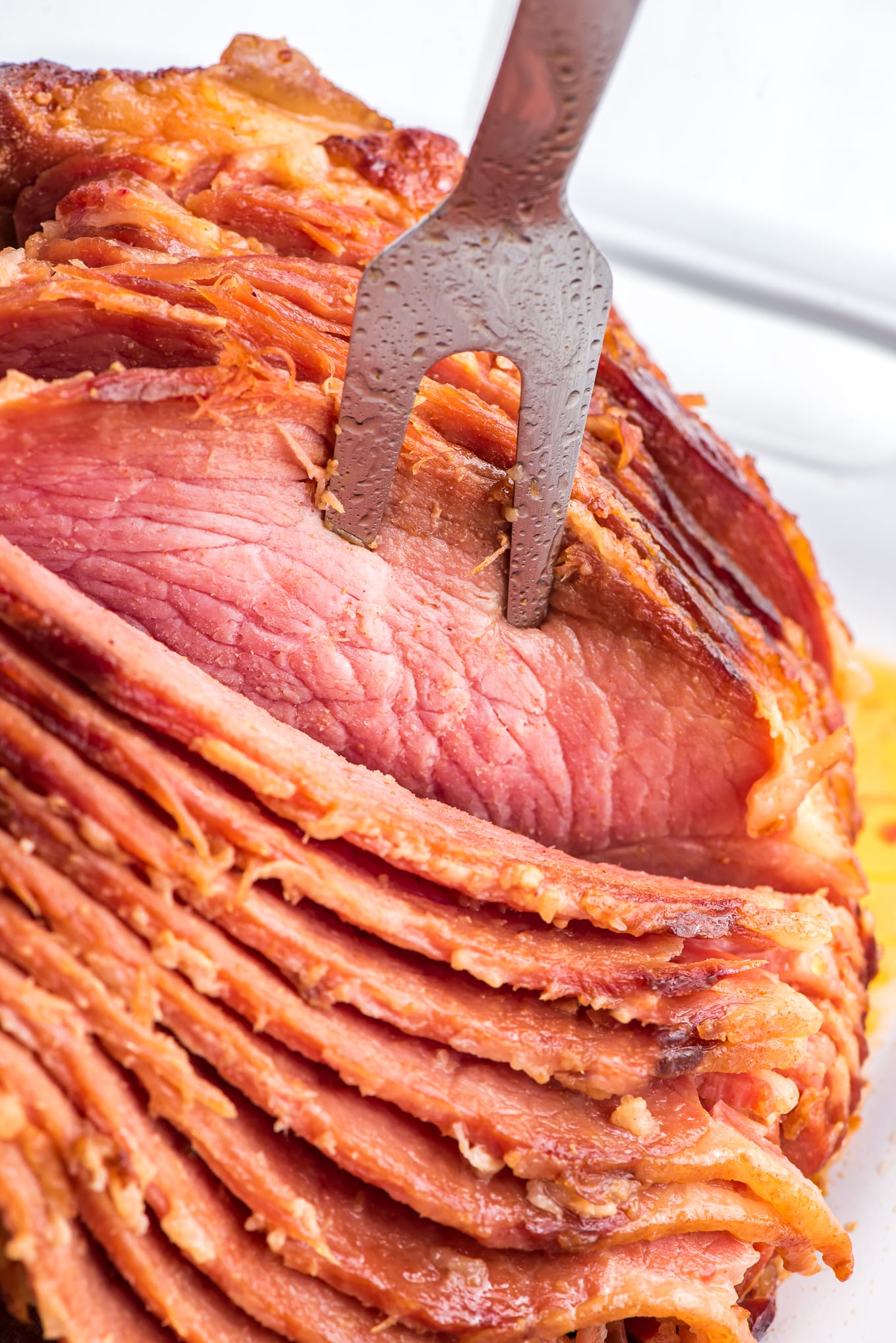 spiral ham on serving plate with a serving fork./