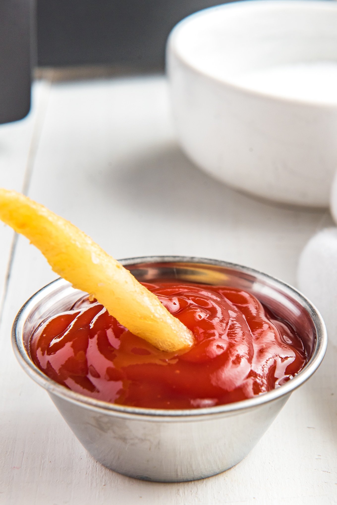 air fryer french fry dipped in ketchup./ Enjoy crispy and delicious frozen French fries in minutes with this easy air fryer recipe. Get that classic crispy texture and savory flavor you love, with the convenience of the air fryer.