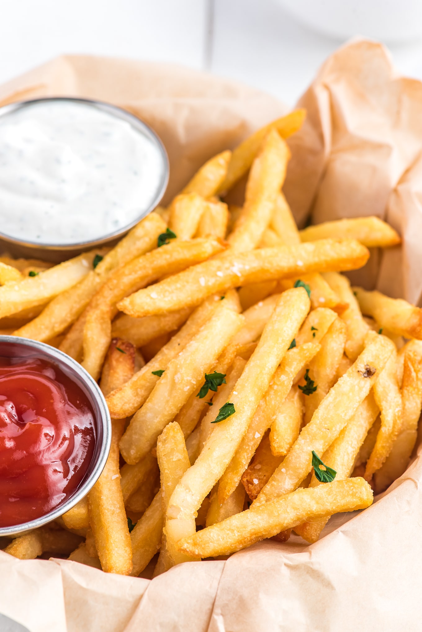 basket of air fryer fries with ketchup and ranch dressing./Enjoy crispy and delicious frozen French fries in minutes with this easy air fryer recipe. Get that classic crispy texture and savory flavor you love, with the convenience of the air fryer.