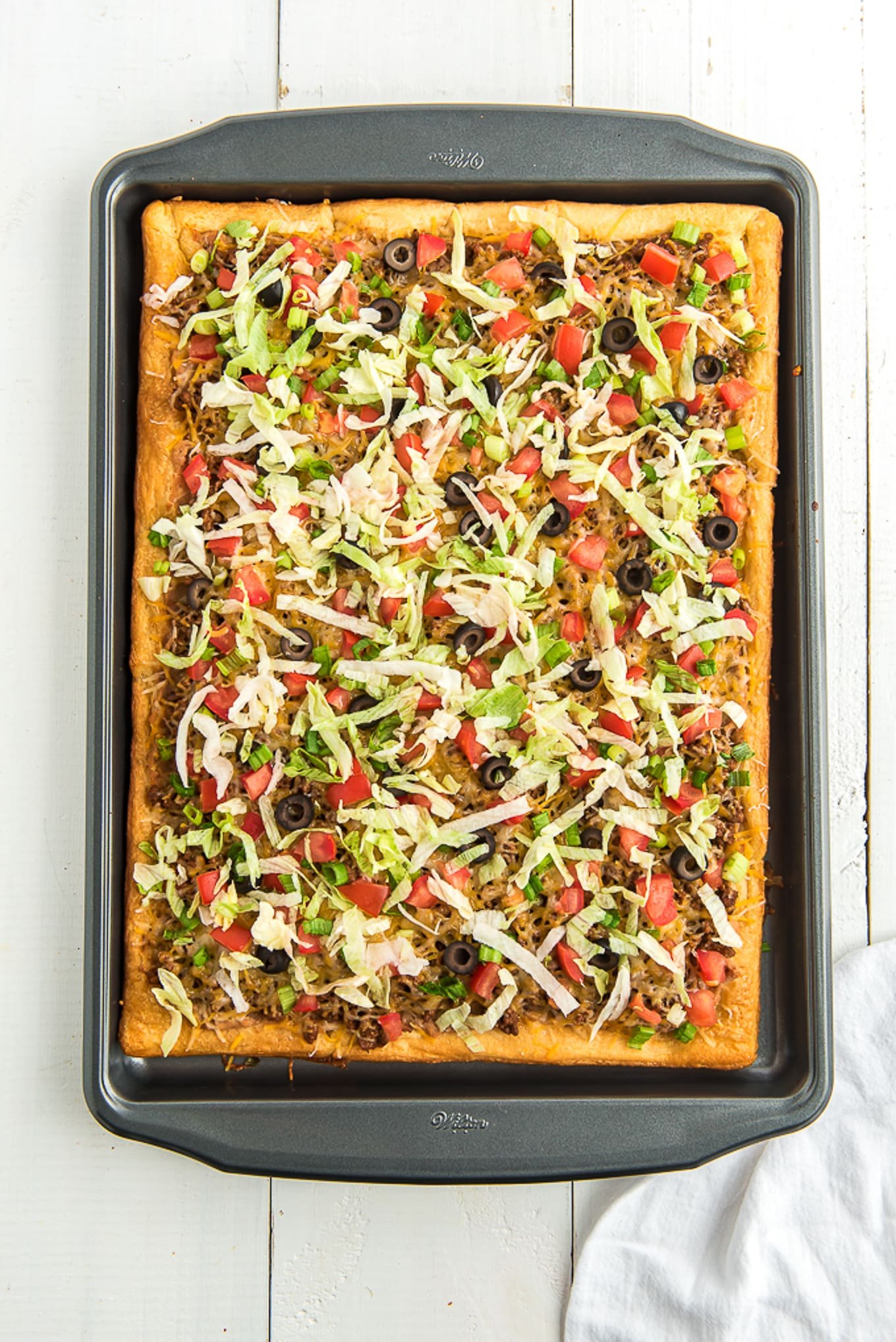 taco pizza on baking sheet with taco toppings./