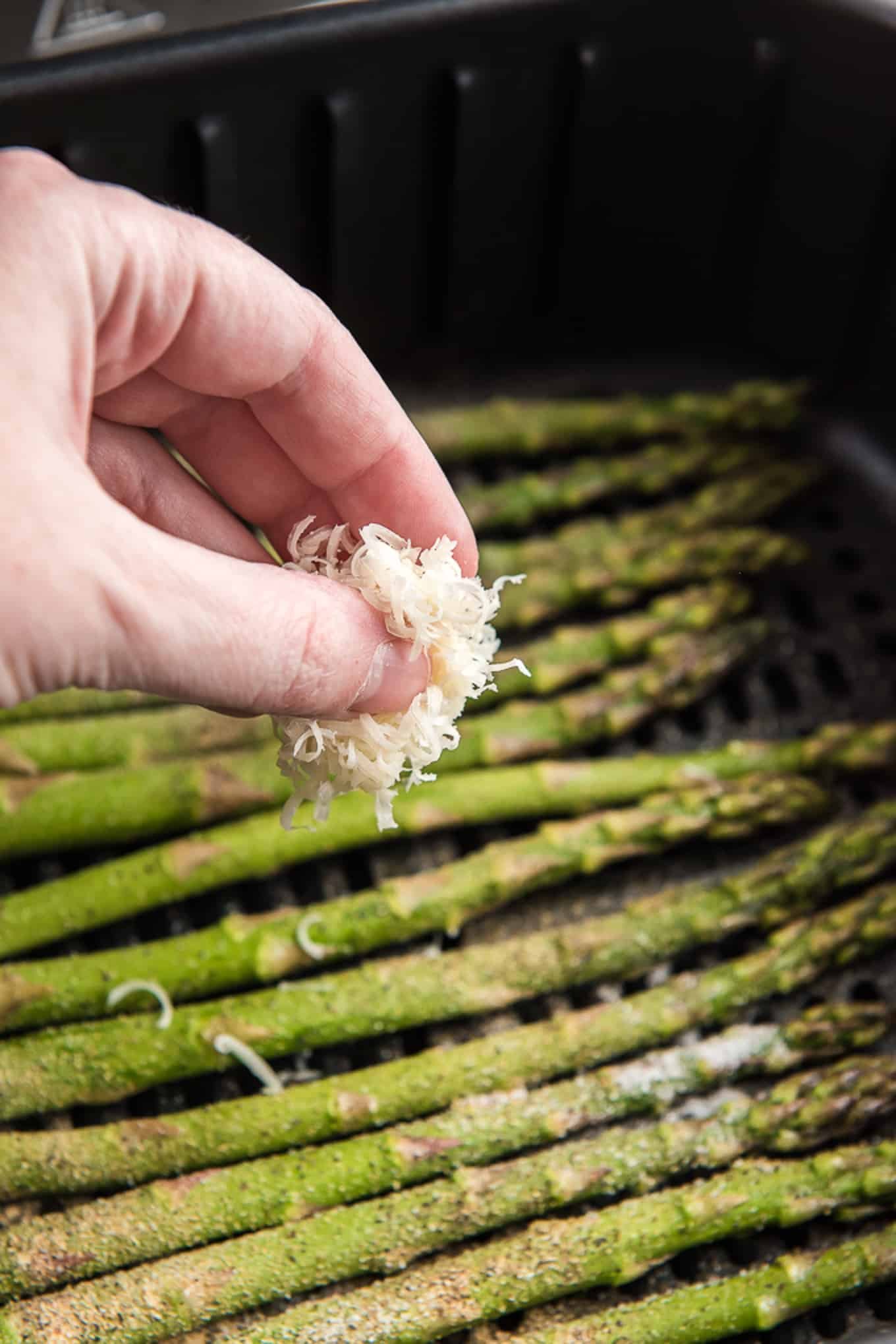 Sprinkling asparagus with parmesan cheese. 