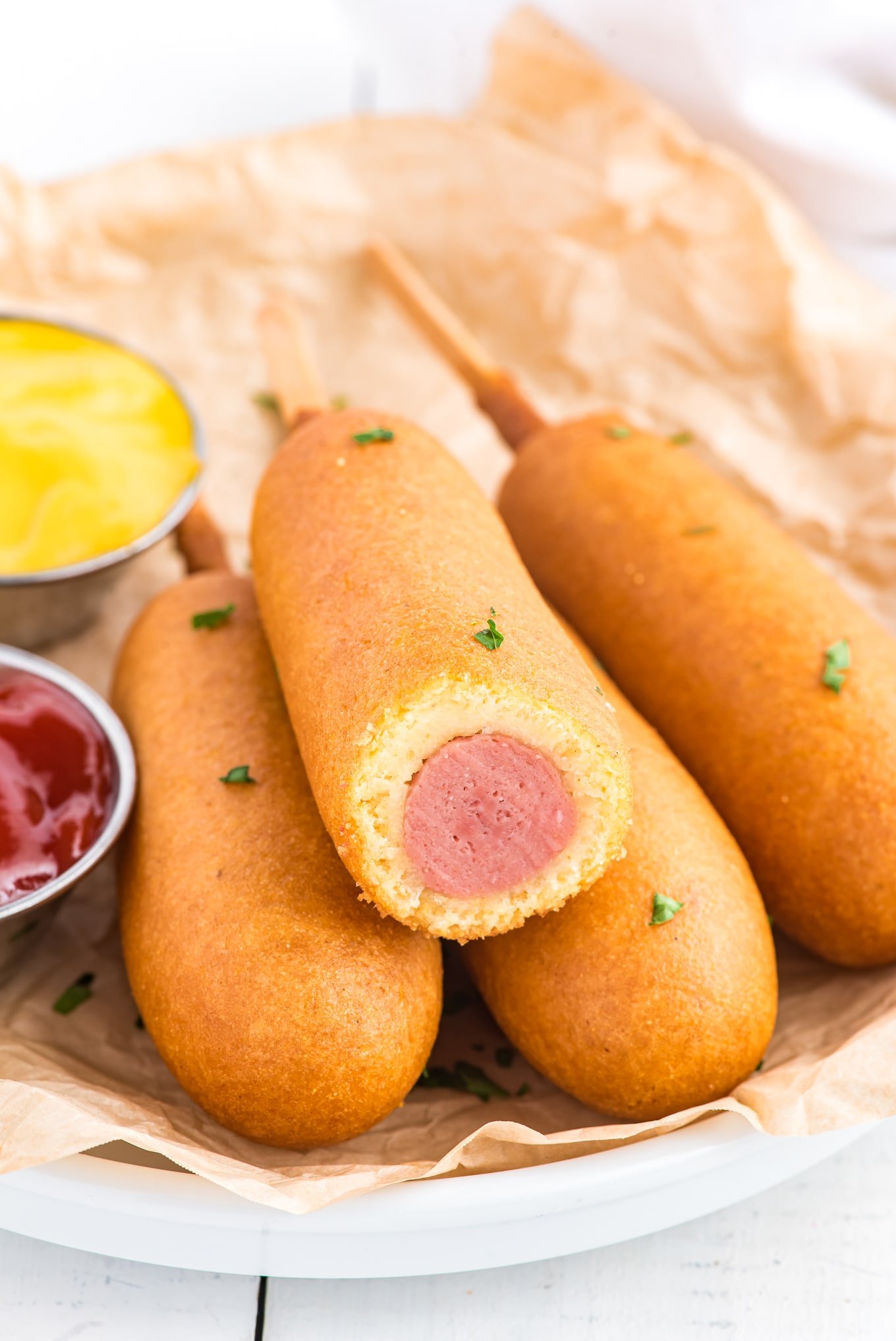 A close-up photo of four corn dogs on a plate.