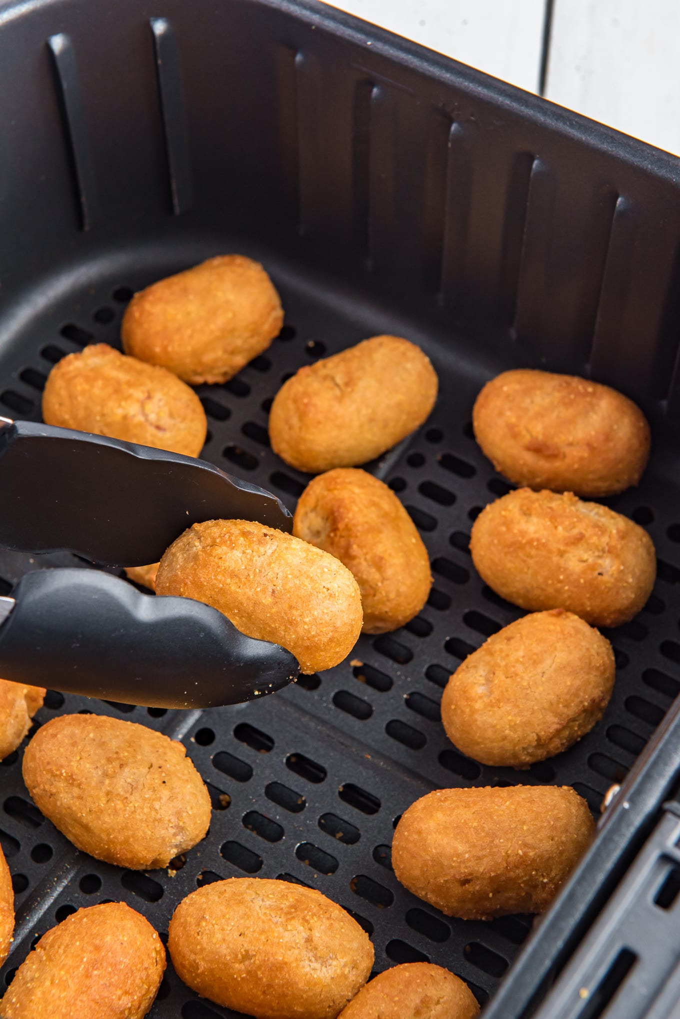 A close-up photo of mini corn dogs in an air fryer basket.