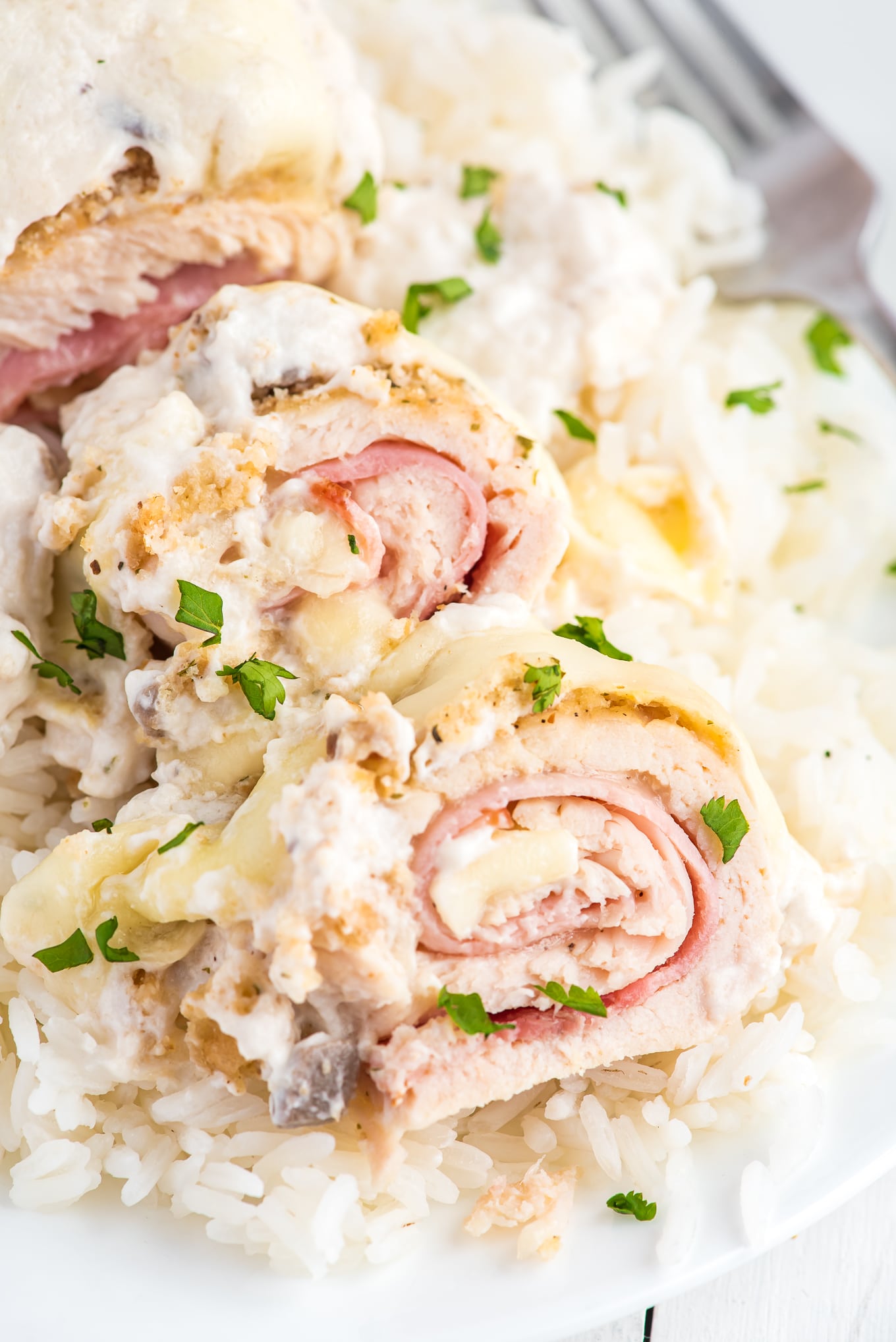 Sliced piece of baked chicken cordon bleu on a plate with rice.