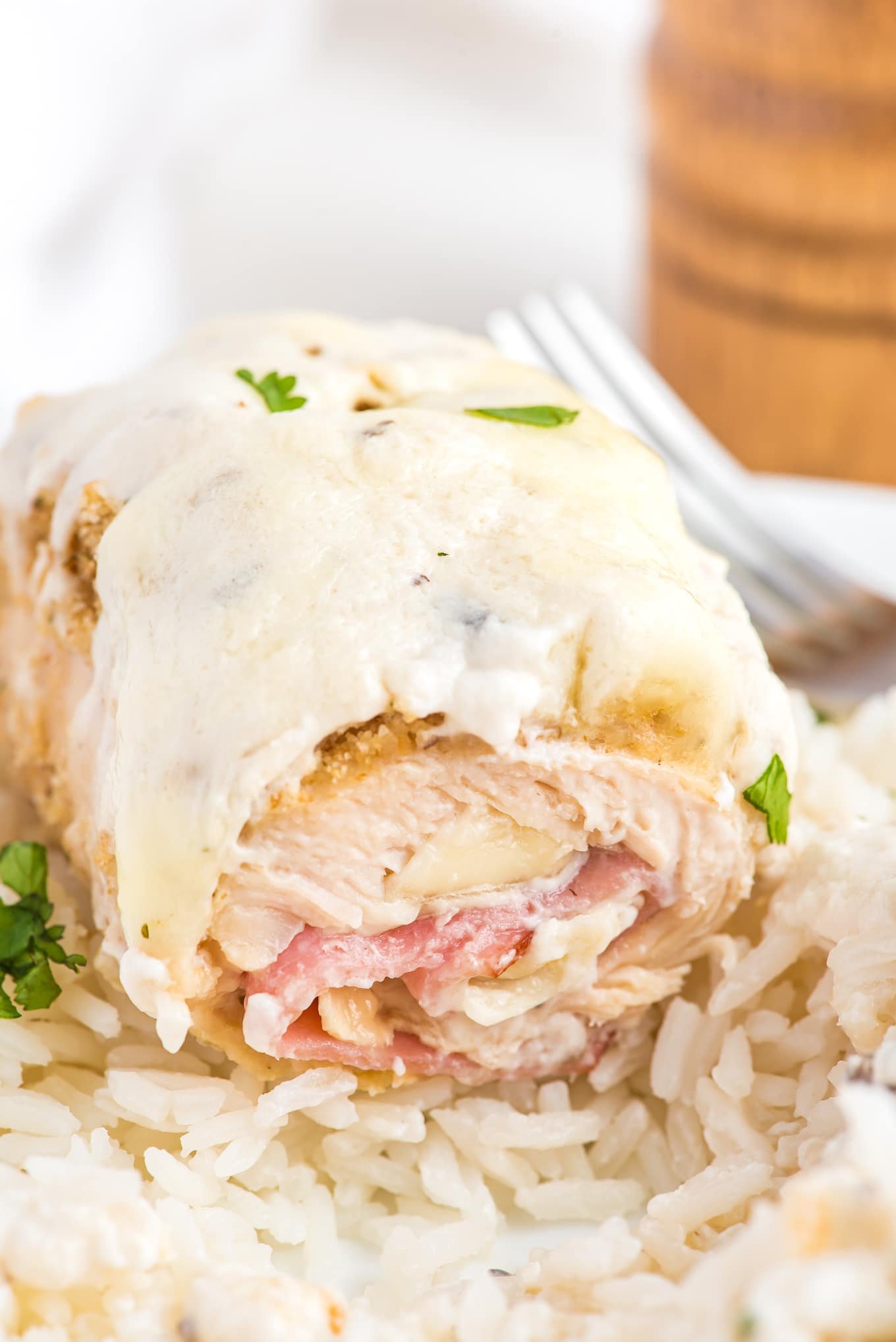 Front view of piece of chicken cut to show the ham, cheese and chicken cordon bleu sauce on top.