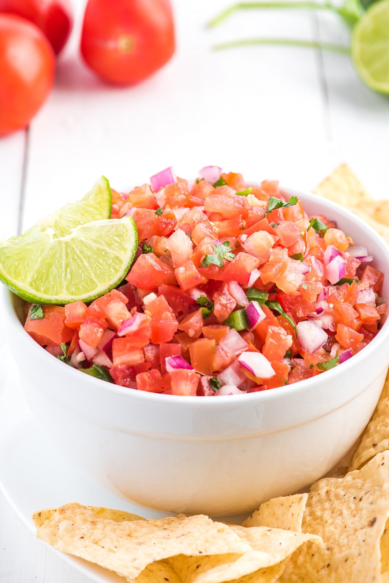 Pico de gallo in a bowl with a lime wedge for garnish.