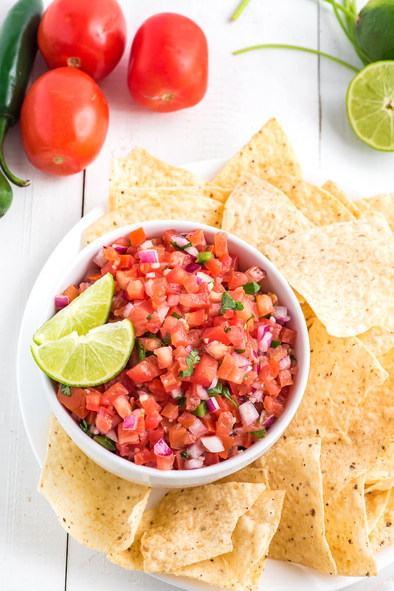 Tomato pico de gallo on a plate with chips and limes.