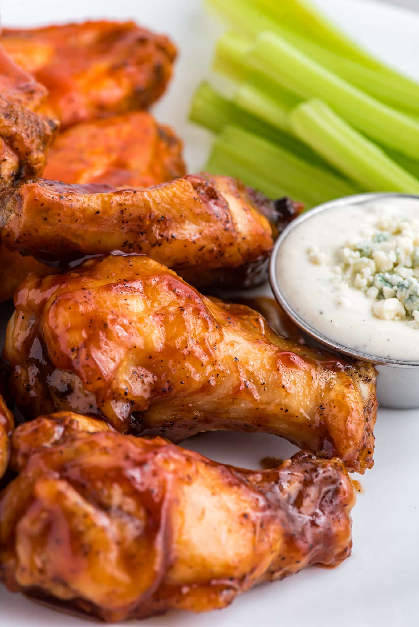 Seasoned and sauced chicken wings next to blue cheese dressing, made in the air fryer. 