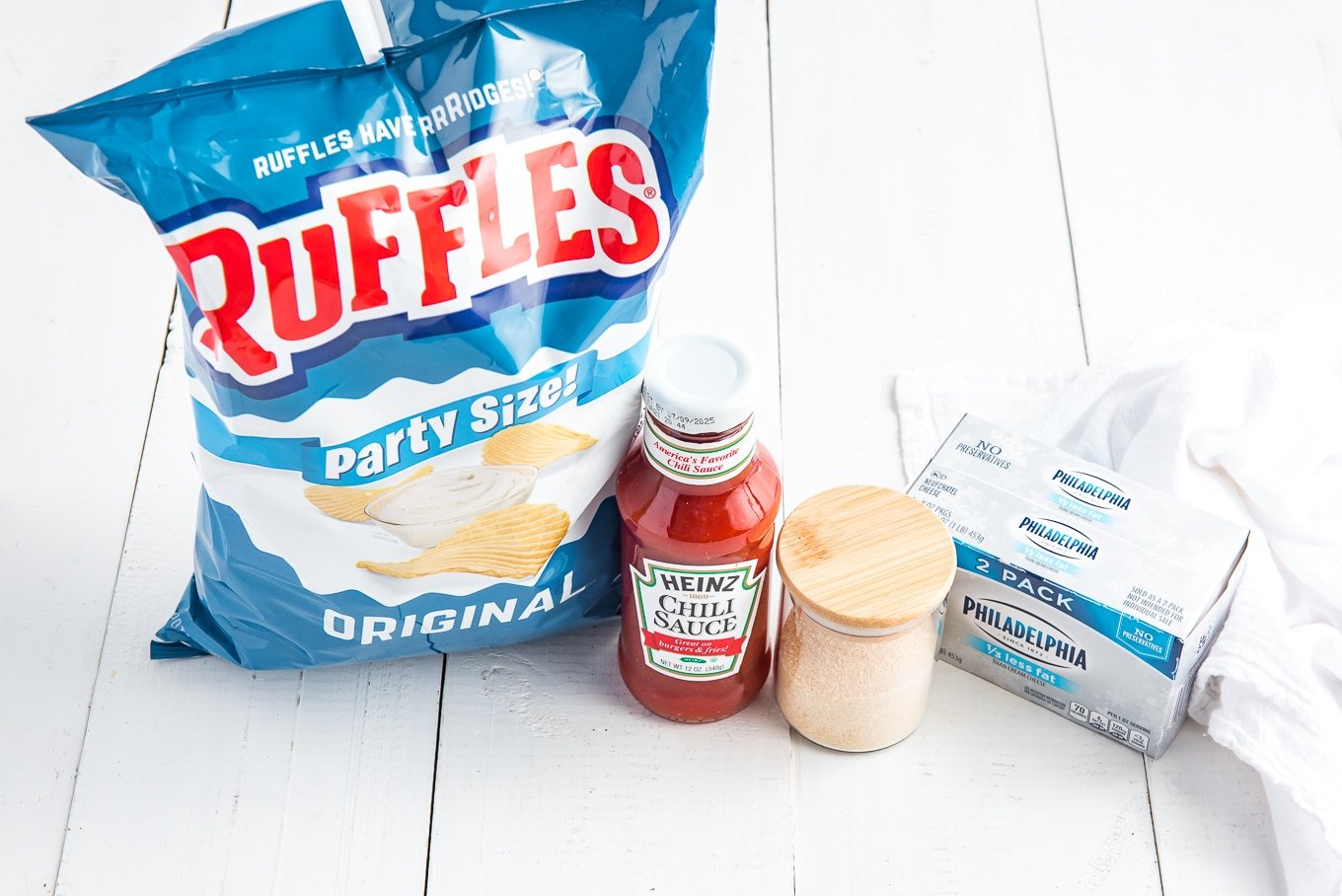 All of the ingredients for the best potato chip dip: Heinz chili sauce, cream cheese, onion salt, and potato chips.