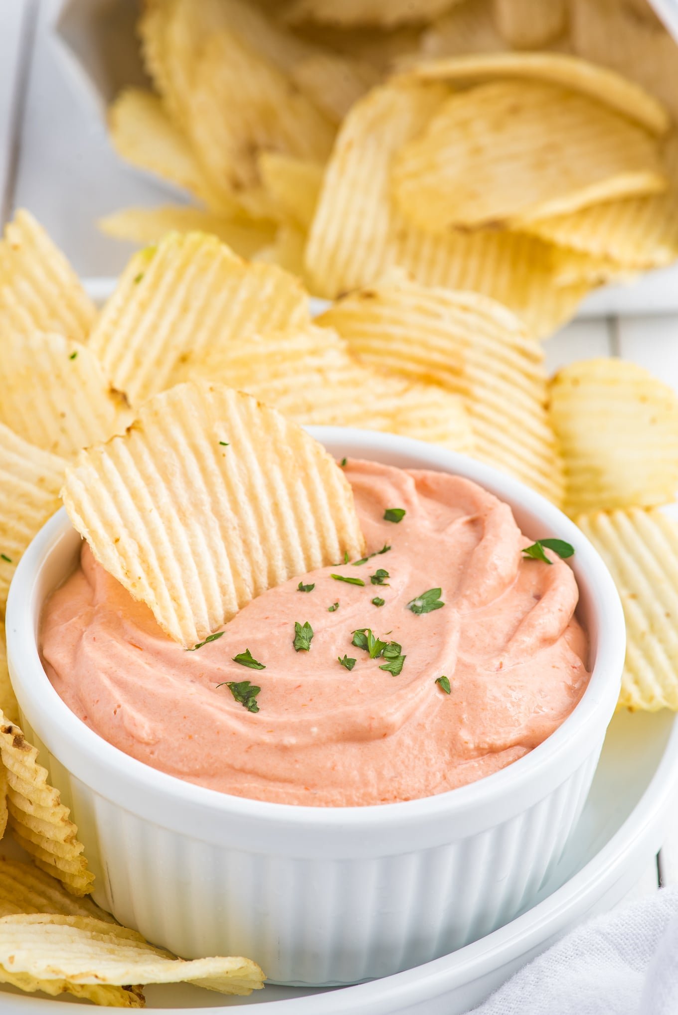 An overhead shot of small bowl of potato chip dip with chips in the background.
