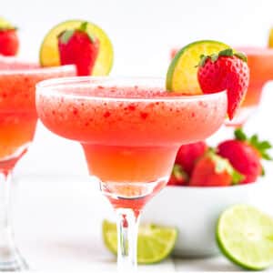 Strawberry margarita in a glass with strawberry and lime garnish.