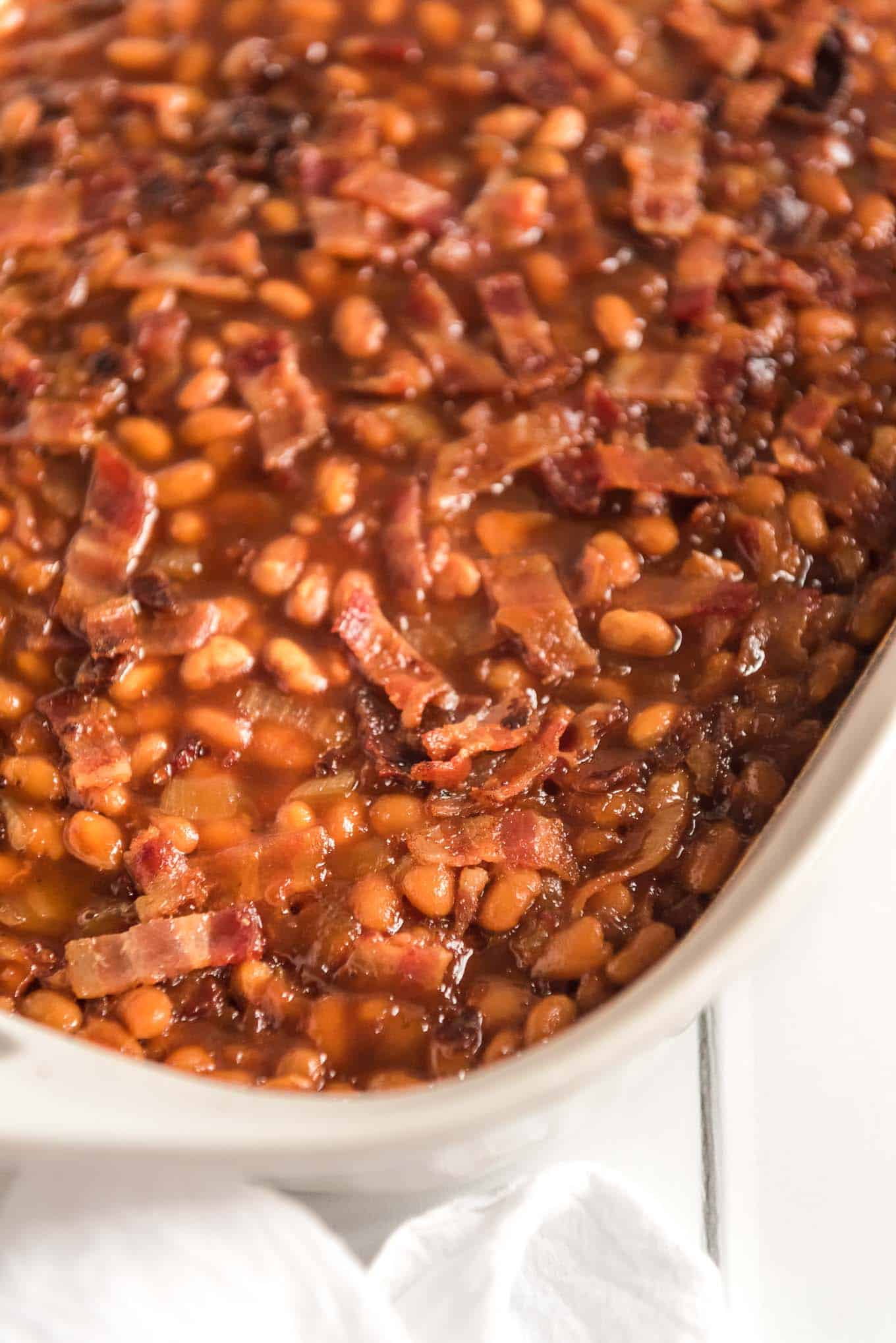 BBQ baked beans in a casserole dish topped with bacon.