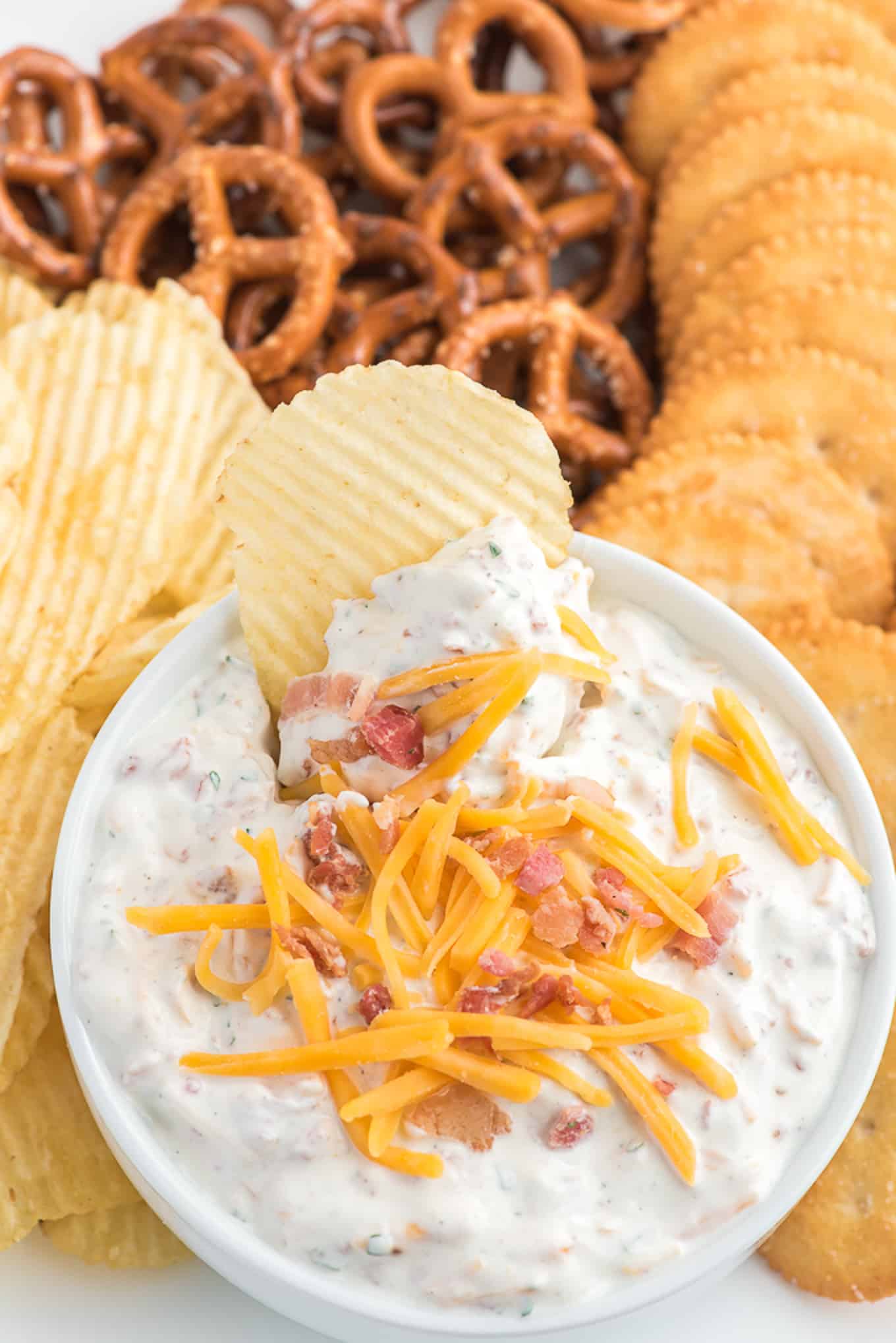 A ruffles chip in the crack dip garnished with cheddar cheese and bacon bits. 