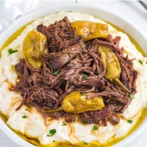 A bowl of mashed potatoes topped with crockpot Mississippi pot roast in a bowl.
