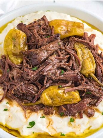 A bowl of mashed potatoes topped with crockpot Mississippi pot roast in a bowl.