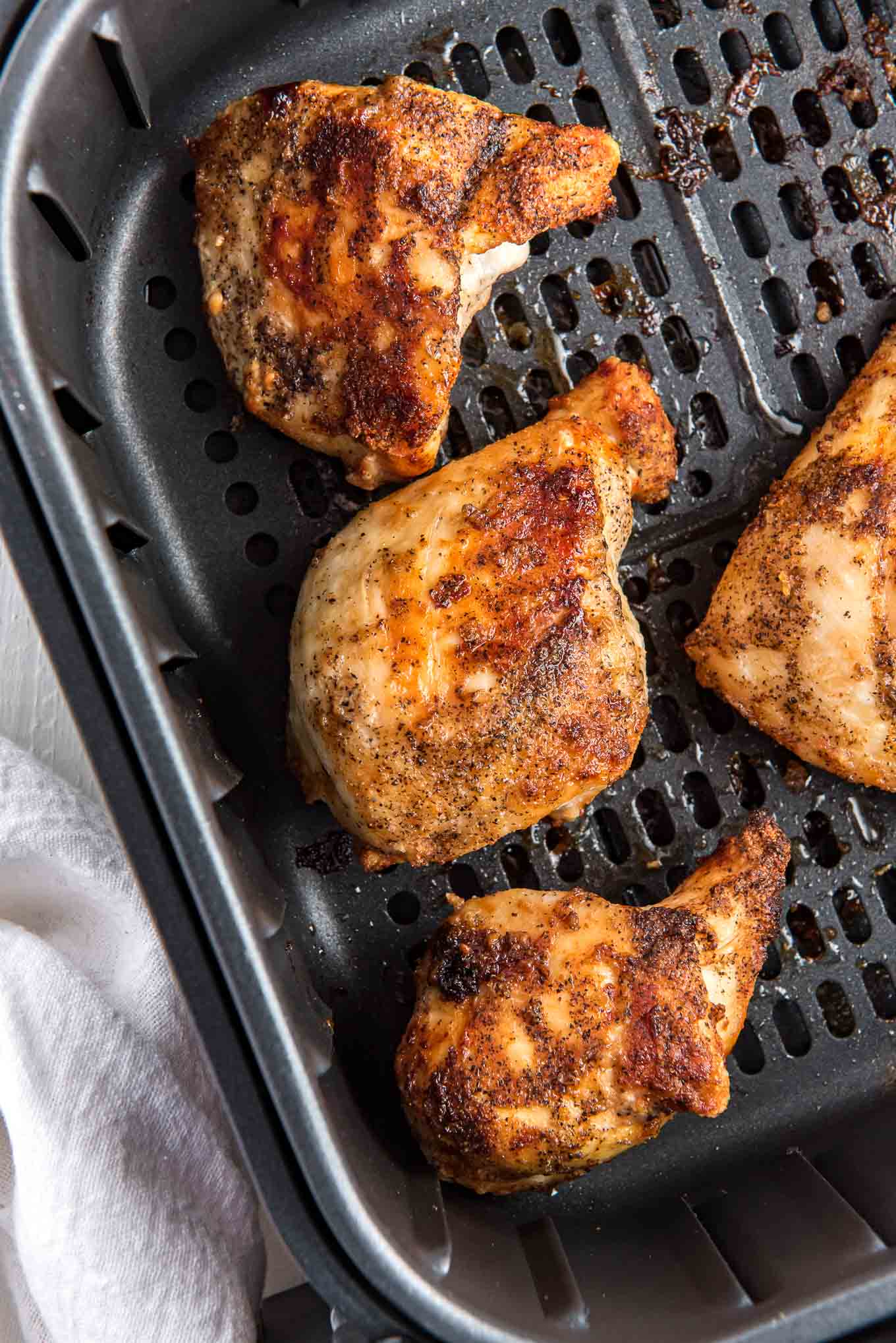 Seasoned chicken breasts at the bottom of the air fryer. 