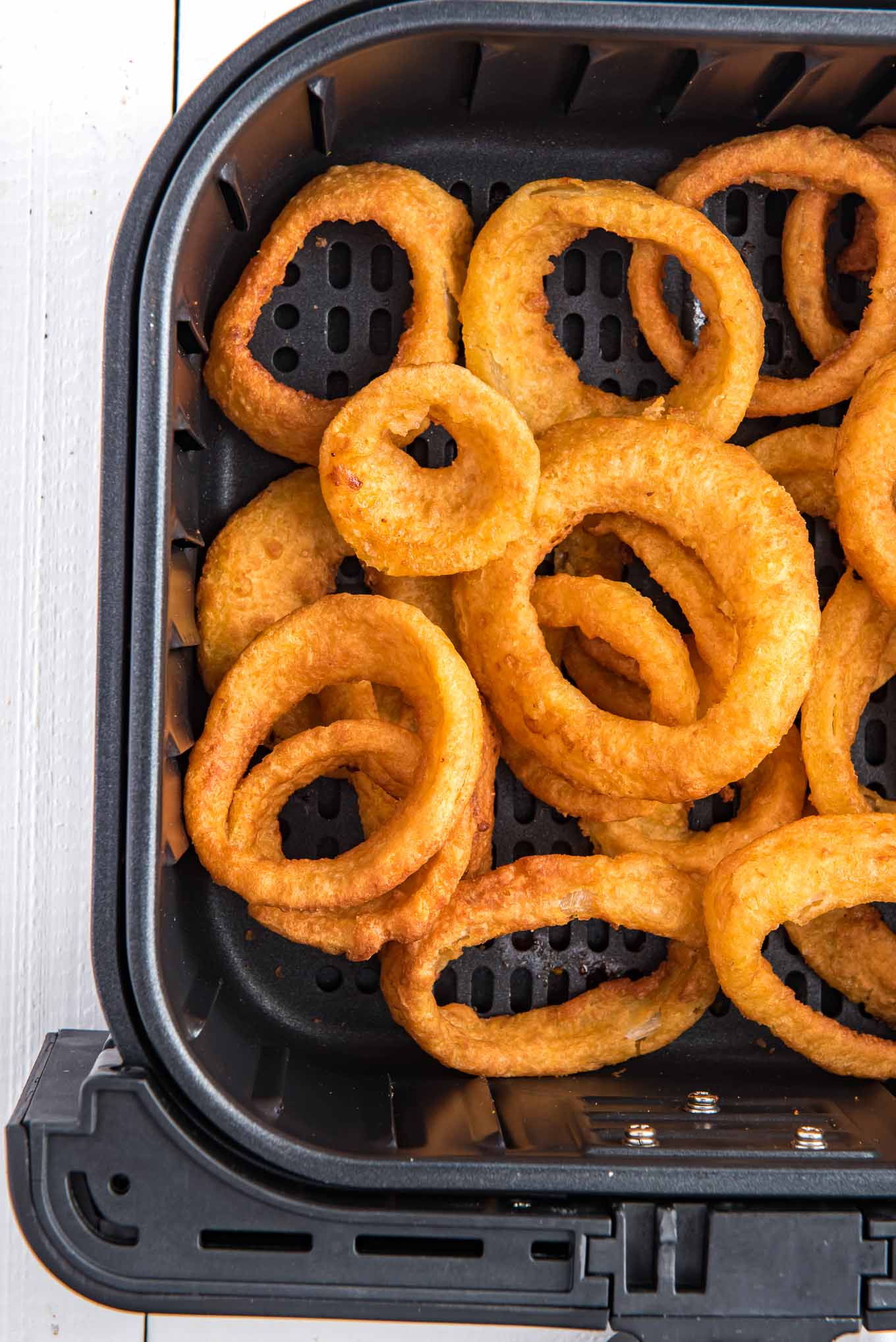 Onion rings are placed in a single layer in the air fryer basket.
