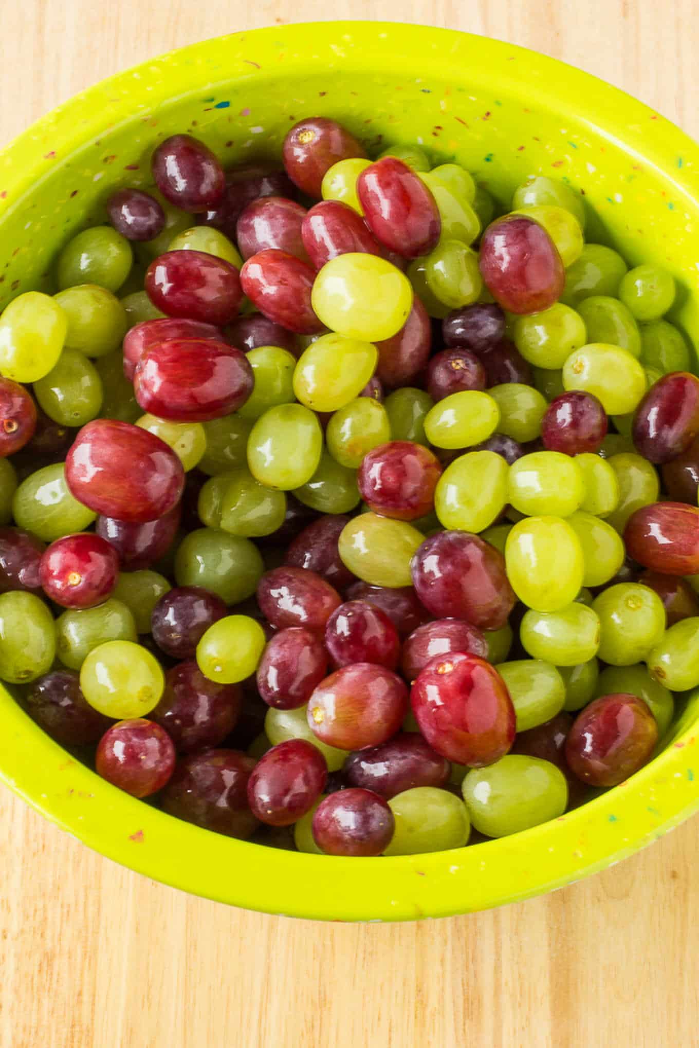 A bowl of washed fresh red and green grapes on the table.