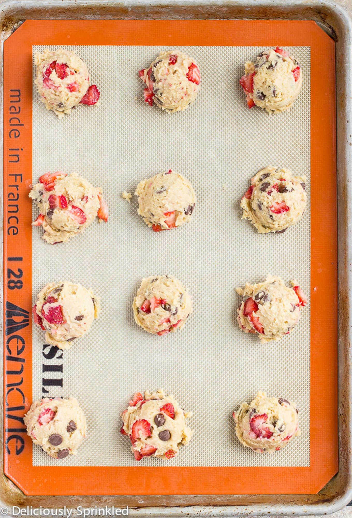 Strawberry cookie dough scooped onto a baking tray.