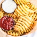 Tasty air fried waffle fries in a parchment paper lined basket.