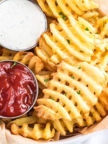 Tasty air fried waffle fries in a parchment paper lined basket.