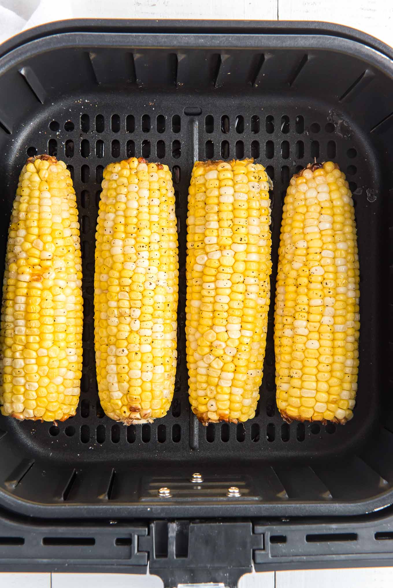 Air fryer corn on the cob in the air fryer basket.