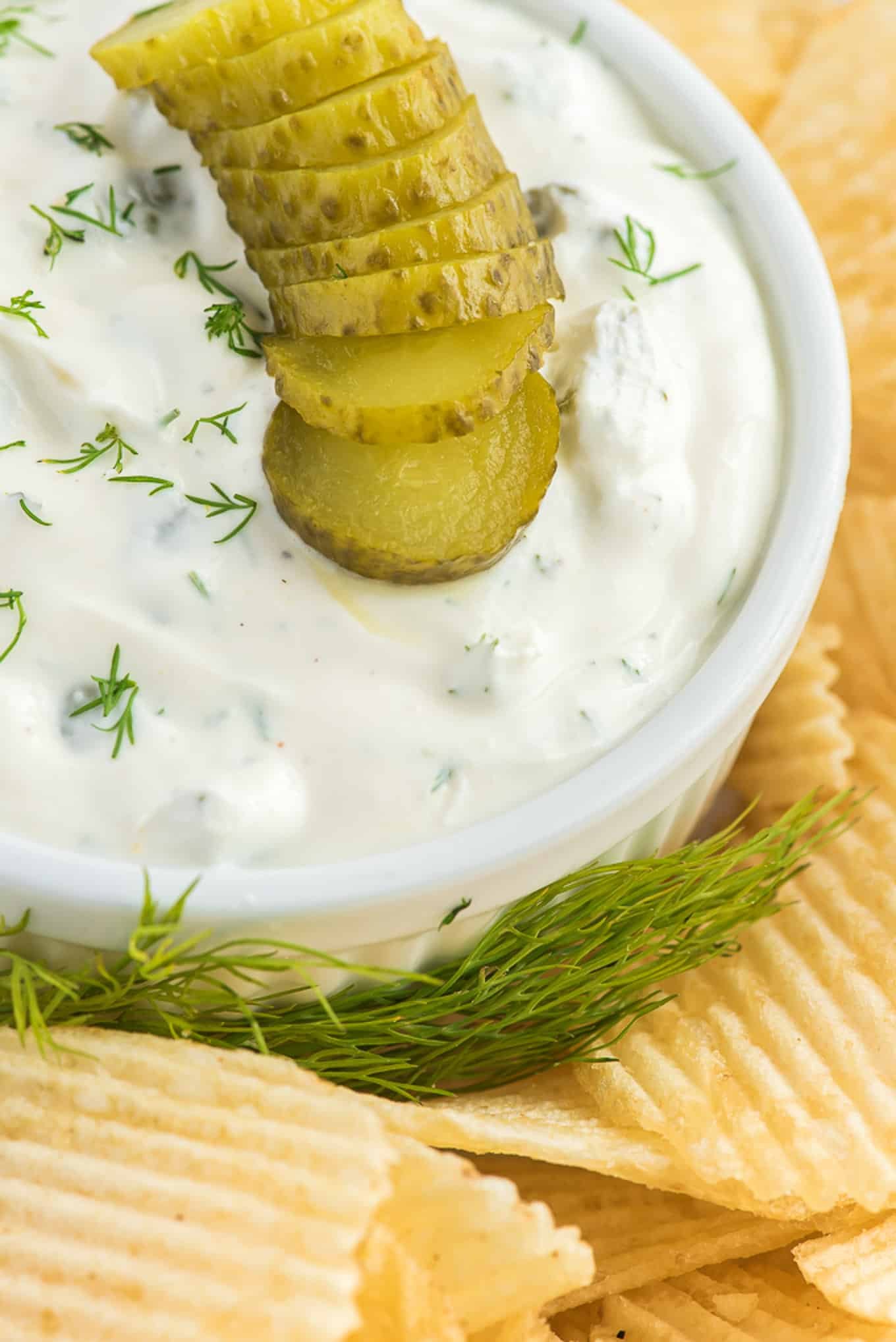 Dill dip garnished with dill and pickles.