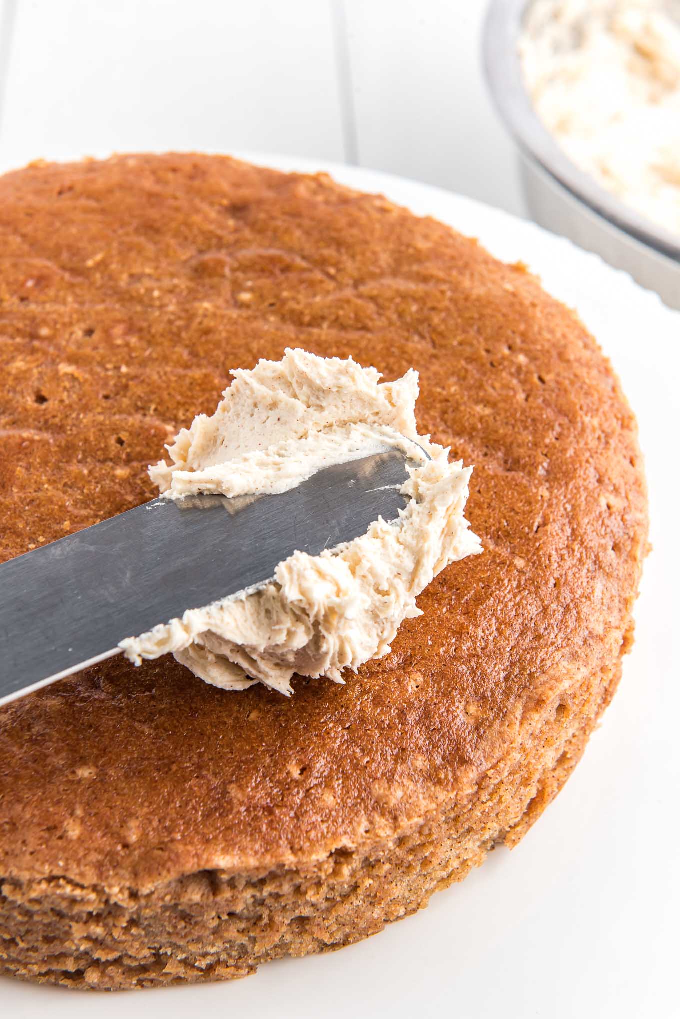 a cake knife frosting one layer of cinnamon cake. 